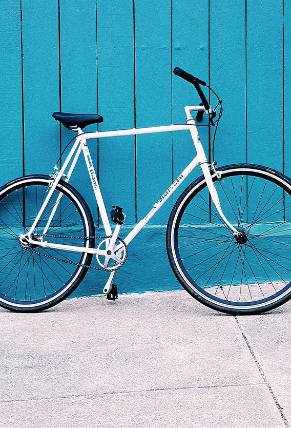 White bicycle parked against blue wall.