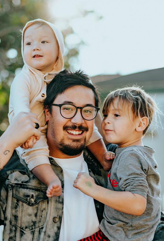 Person with glasses and bleached denim jacket with two children.